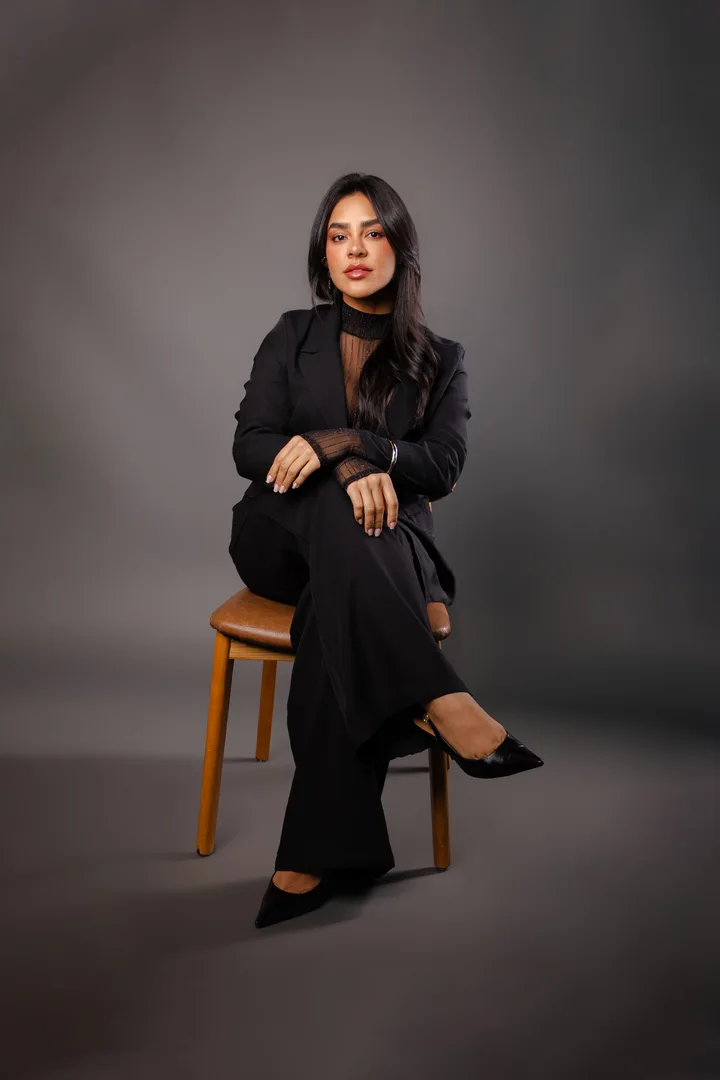 Dra. Karolyna Ribeiro sentada, usando traje preto
