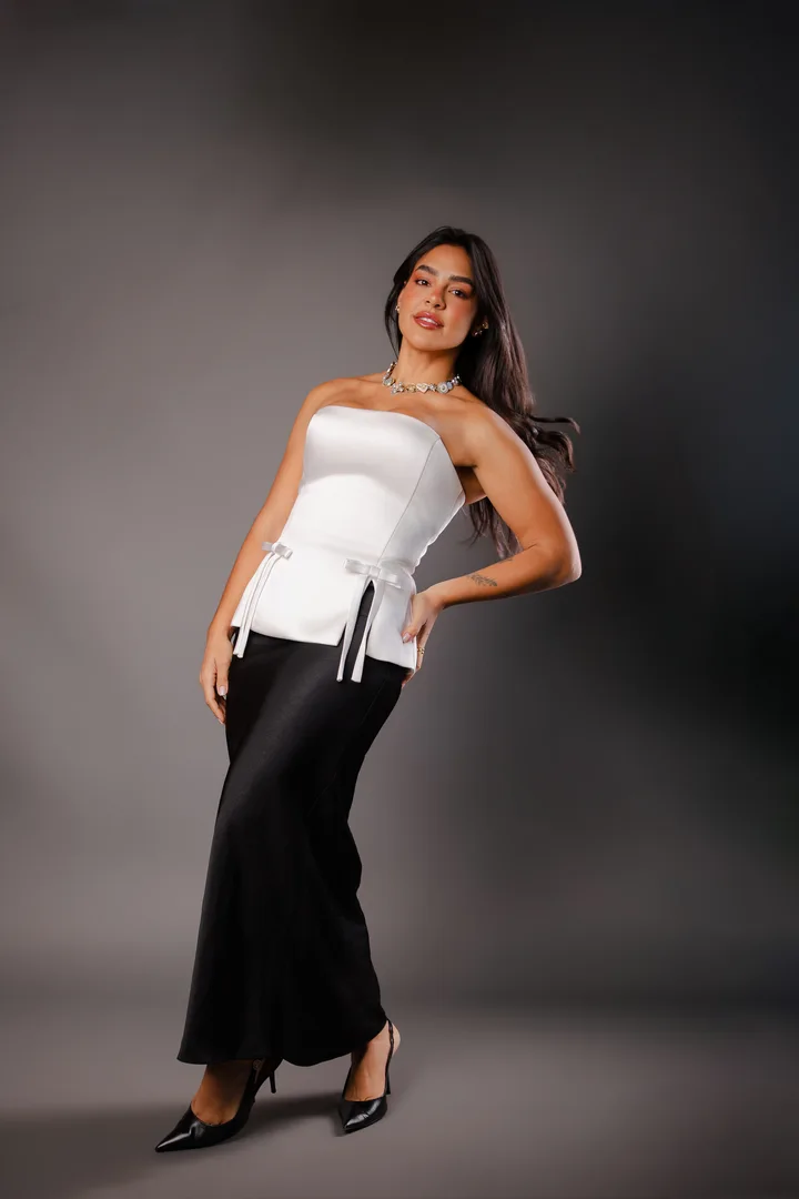 Dra. Karolyna Ribeiro em traje branco e preto, em pé
